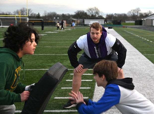 Center, Ben Wrather, a Northwestern University senior and offensive lineman from Powell, Ohio, works with young athletes during a GBN Jr. Spartan Football clinic at William Lutz Stadium at Glenbrook North High School on April 7, 2024. (Karie Angell Luc/Pioneer Press)