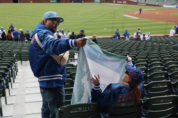 Two fans check out Cubs fleece blankets given to people entering Wrigley Field before a game against the Marlins on April 20, 2024, in Chicago. (John J. Kim/Chicago Tribune)
