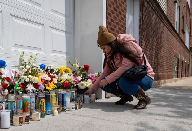 A woman leaves candles, April 28, 2024, at a memorial in Gage Park where Chicago police Officer Luis M. Huesca was shot and killed last weekend. (Brian Cassella/Chicago Tribune)