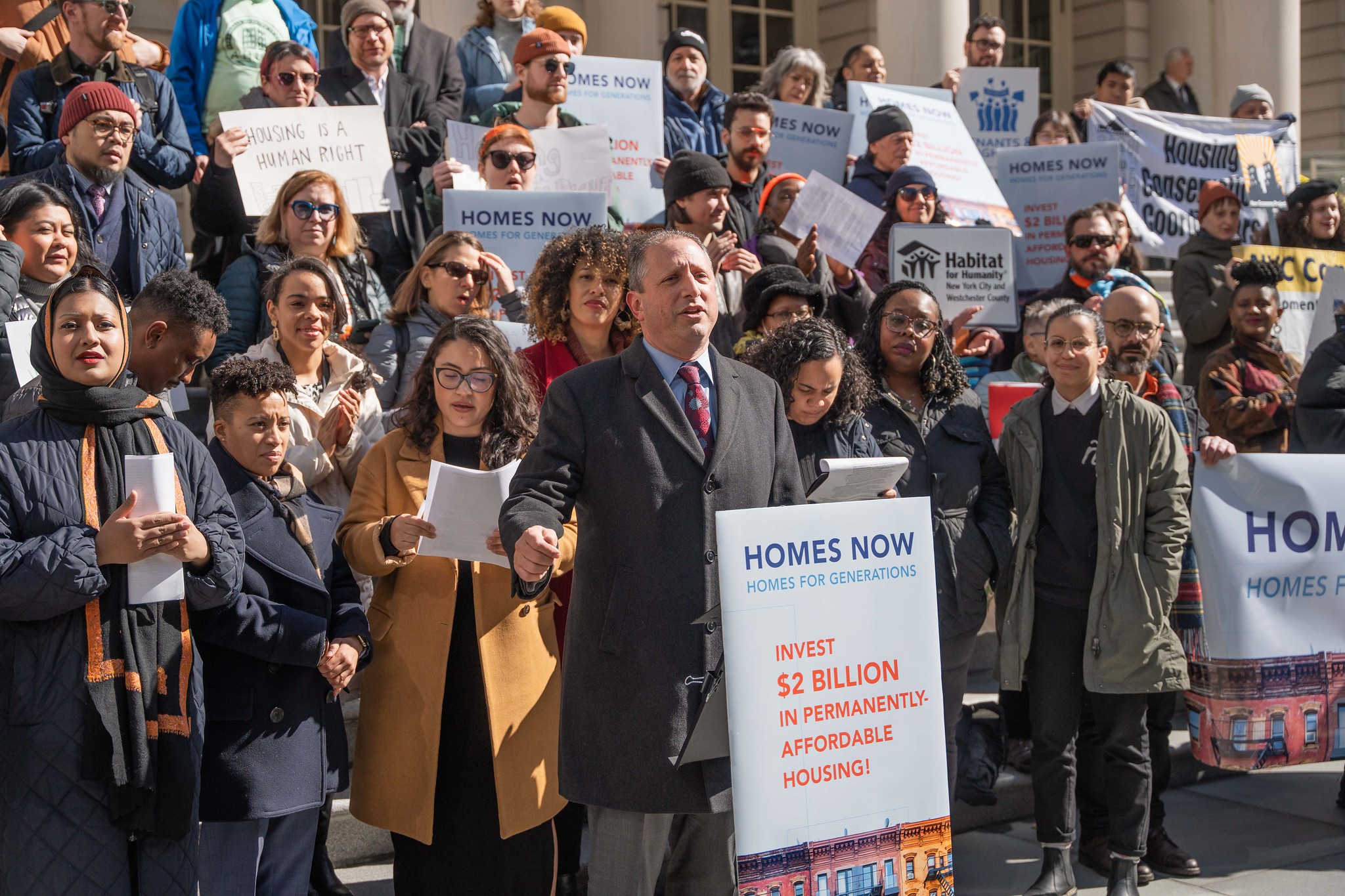 Comptroller Brand Lander on the steps of City Hall surrounded by supporters and lawmakers.