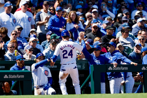 Cubs center fielder Cody Bellinger (24) gets high-fives as he returns to the dugout after scoring against the Marlins on April 19, 2024, at Wrigley Field. (Vincent Alban/Chicago Tribune)