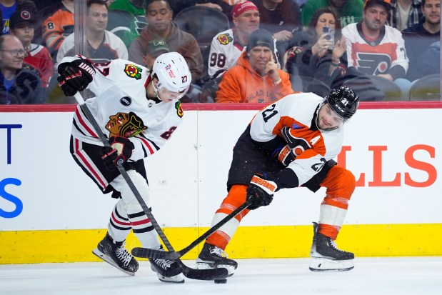 The Blackhawks' Lukas Reichel, left, tries to keep the puck away from the Flyers' Scott Laughton on March 30, 2024, in Philadelphia. (AP Photo/Matt Slocum)