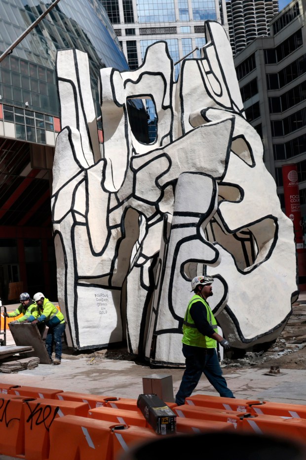 Workers remove the sculpture Standing Beast, by artist Jean Dubuffet, outside the Thompson Center, April 5, 2024, as they prepare to move it to an undisclosed location. (Antonio Perez/Chicago Tribune)