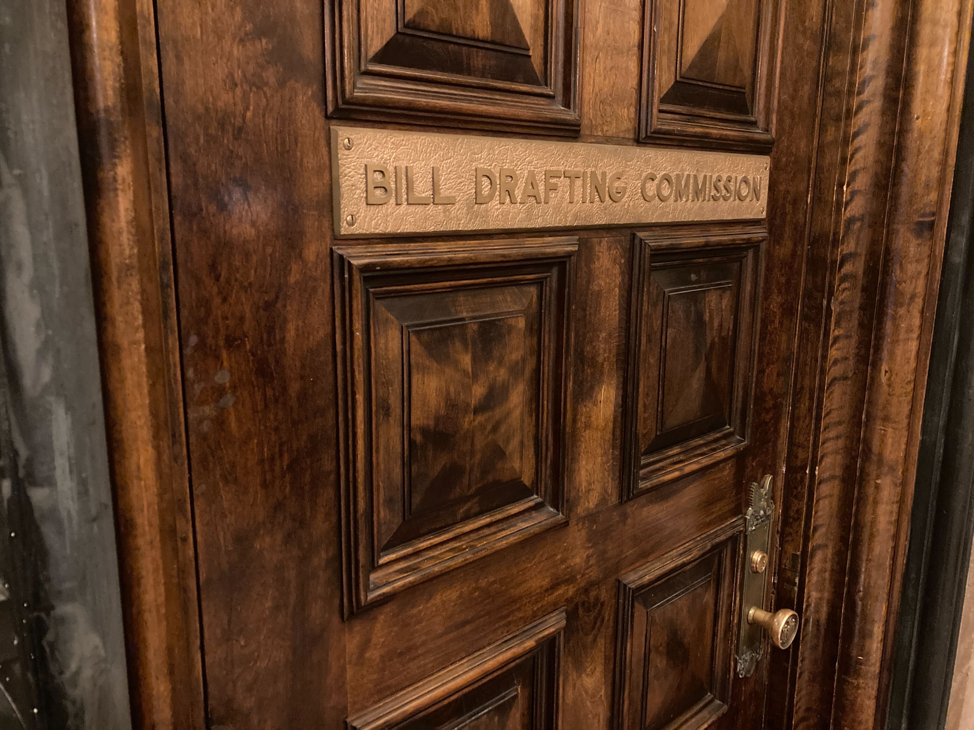 A wooden door at the state Capitol in Albany with a sign saying "bill drafting commission."