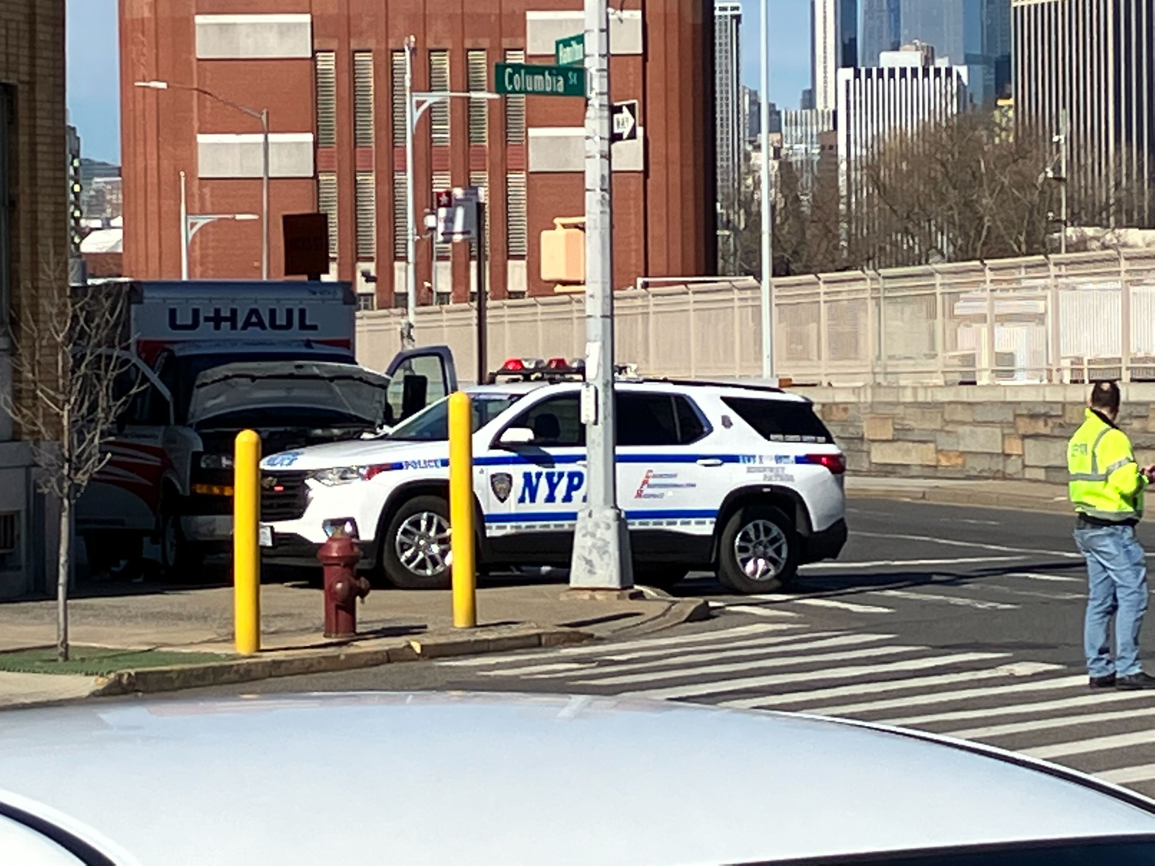 A sidewalk with the U-Haul truck and an NYPD car.