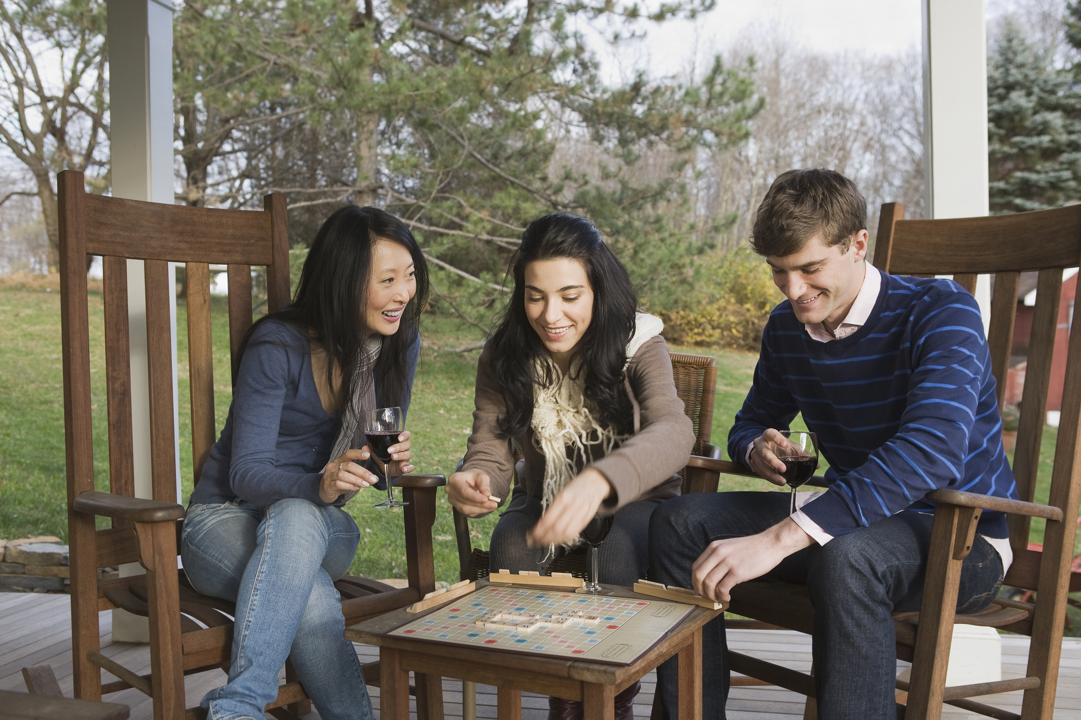 three friends playing scrabble and drinking wine