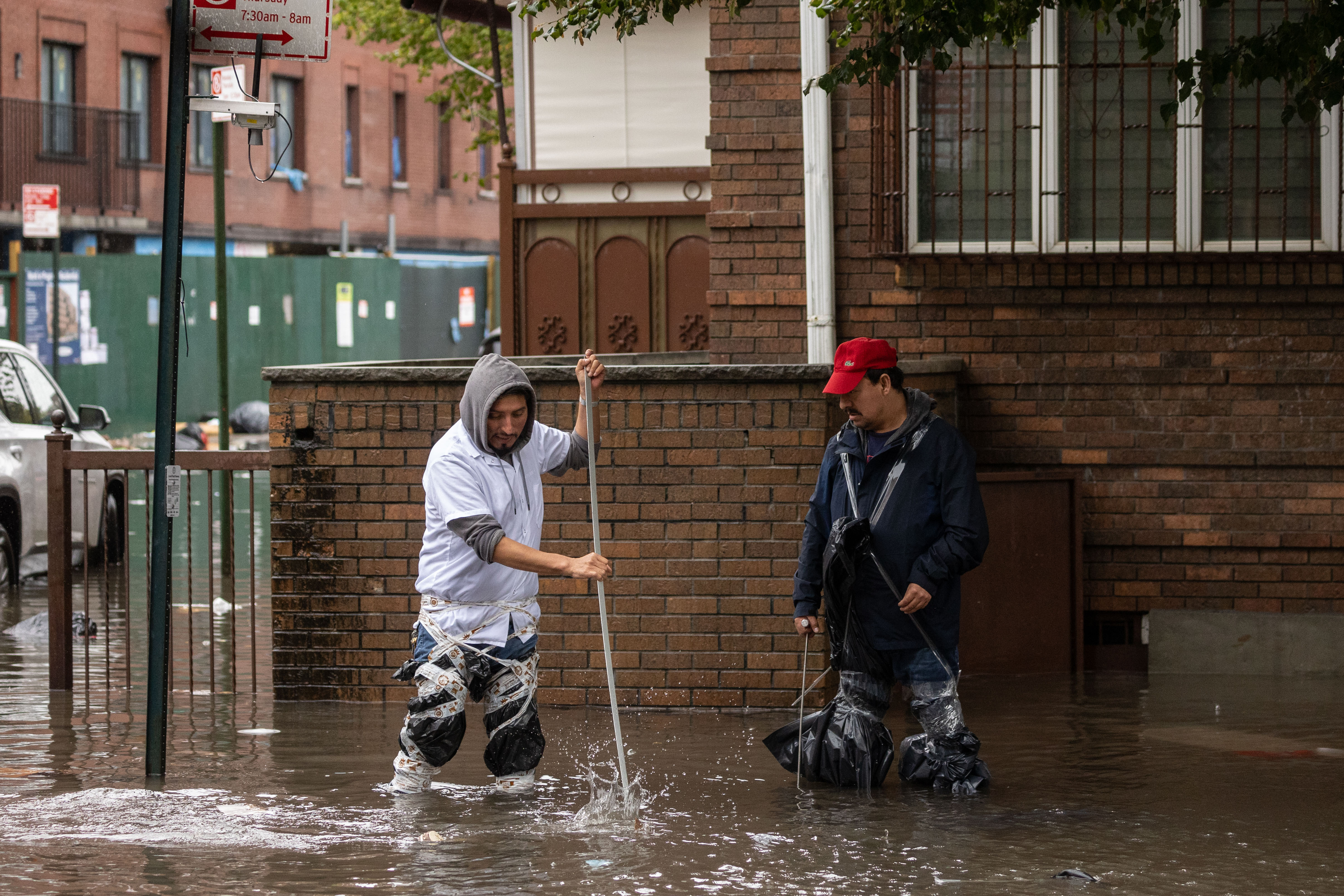 Two men try to clean up sewage in Brooklyn following a storm.