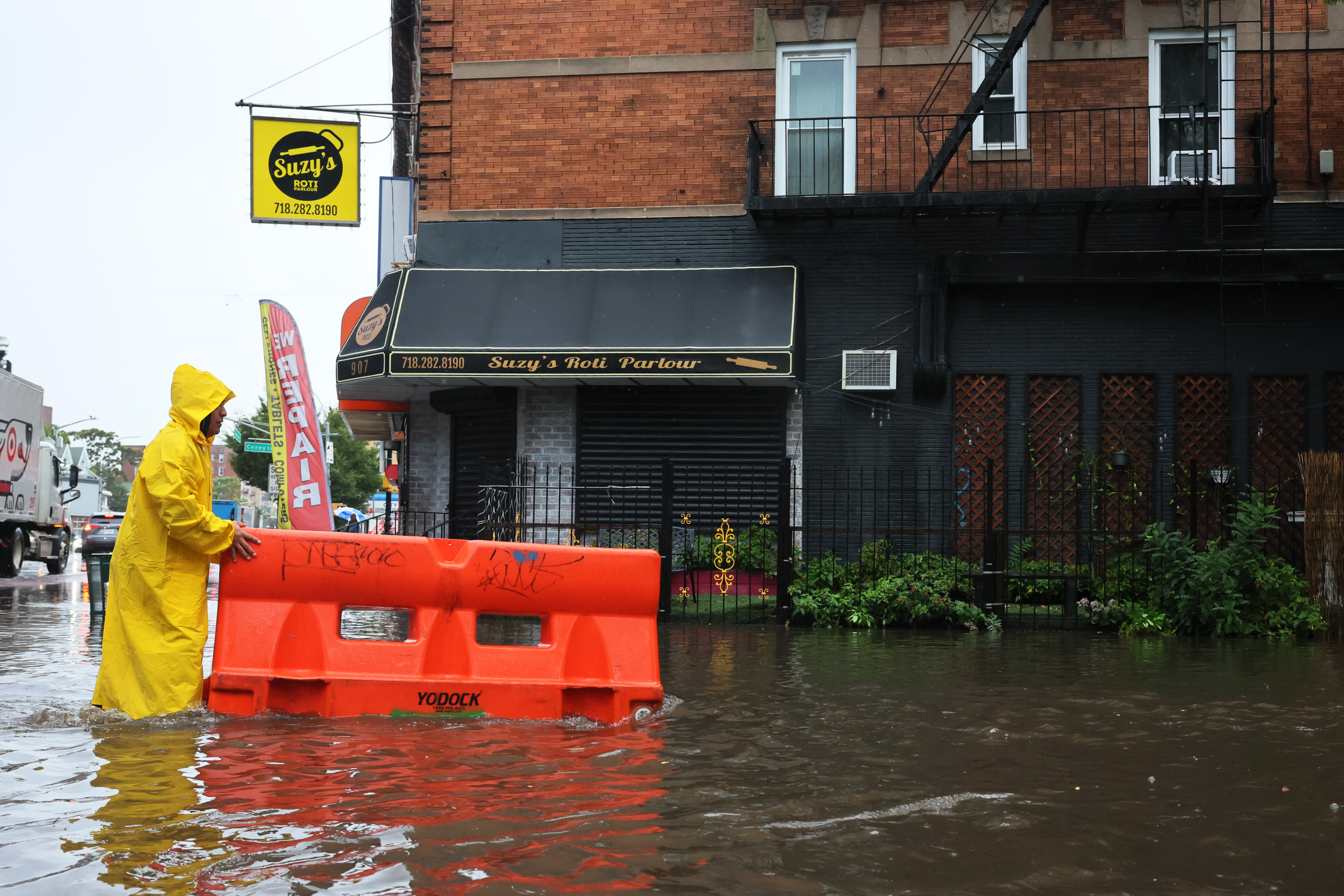 A person pushes a barricade floating on a flooded E 10th Street amid a coastal storm on Sept. 29, 2023 in the Flatbush neighborhood of Brooklyn.