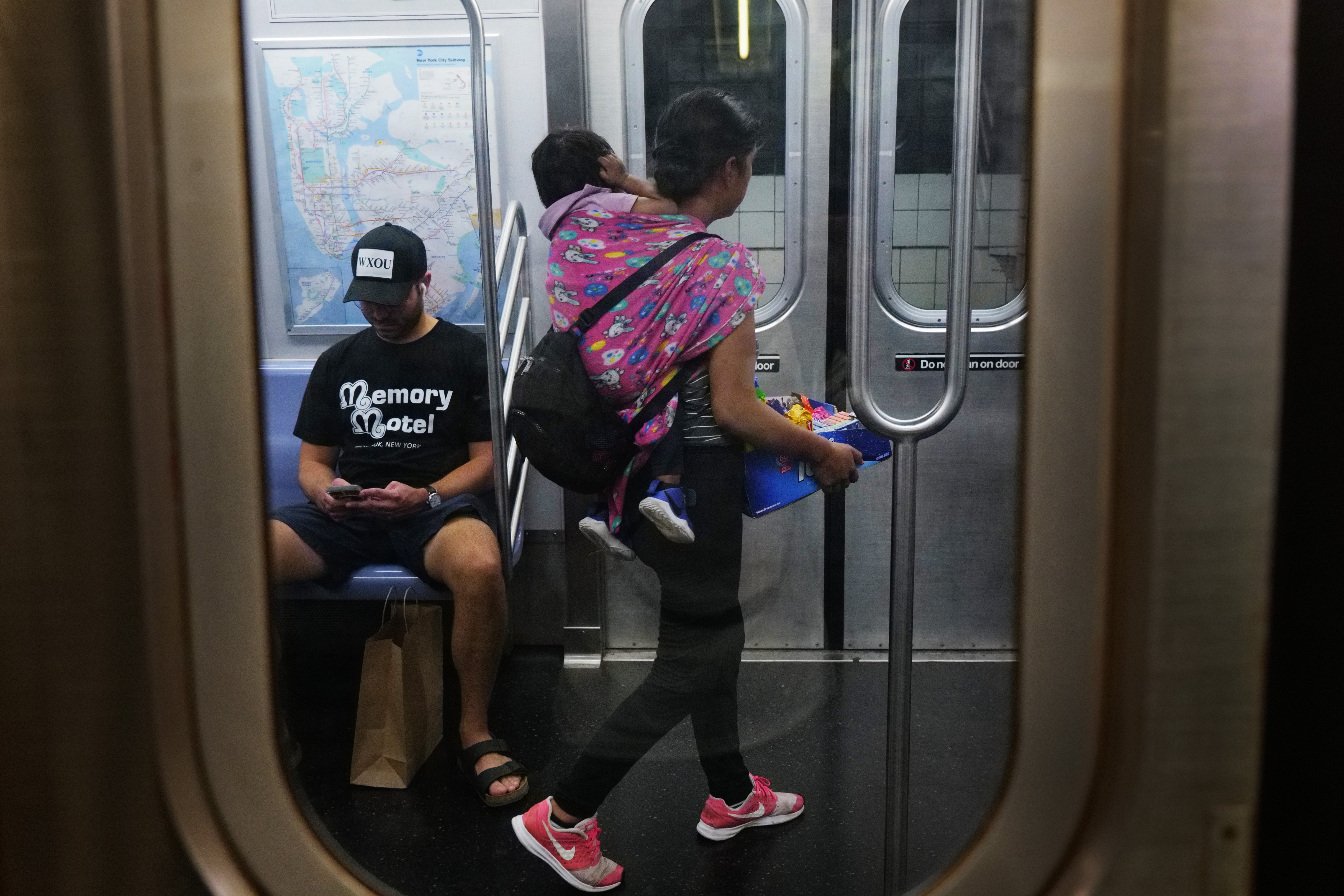 A young woman with a baby sells candy and other items in a New York City subway car on Aug. 18, 2023 in New York City.