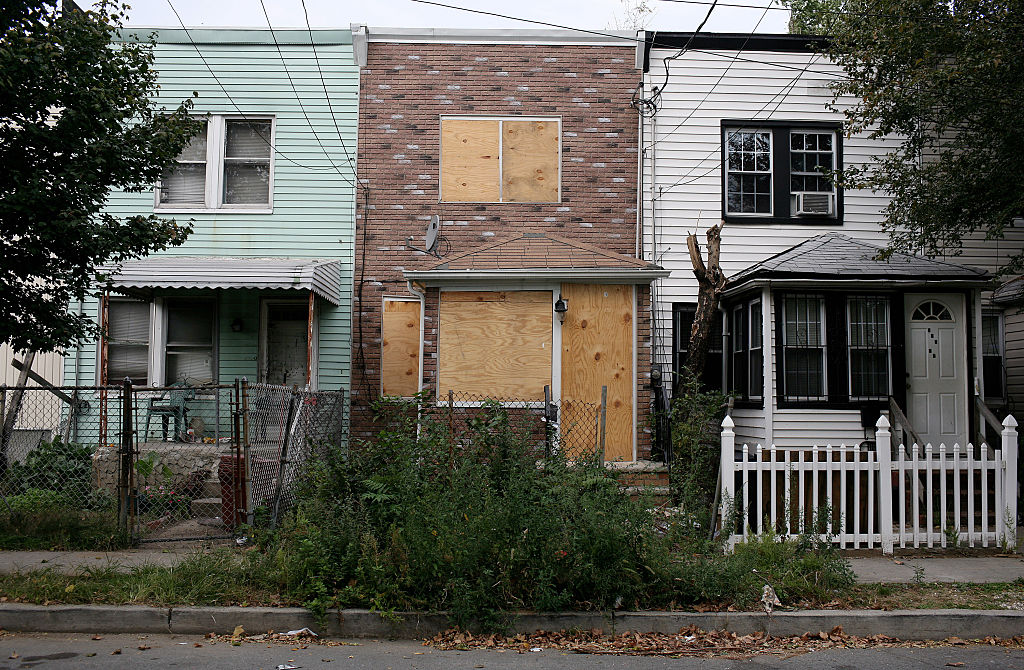 A row of houses in Jamaica, Queens, where one house is boarded up.