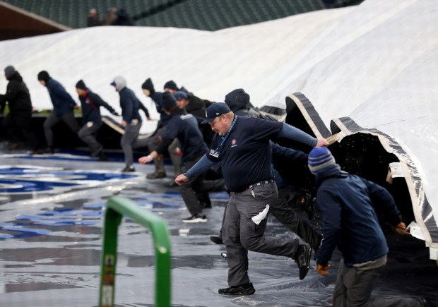 The Wrigley Field grounds crew takes the tarp off the field before a scheduled game between the Chicago Cubs and the Colorado Rockies on Wednesday, April 3, 2024. (Chris Sweda/Chicago Tribune)