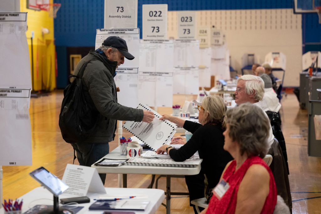 A voter in a baseball cap casts his vote in a gymnasium in Manhattan.