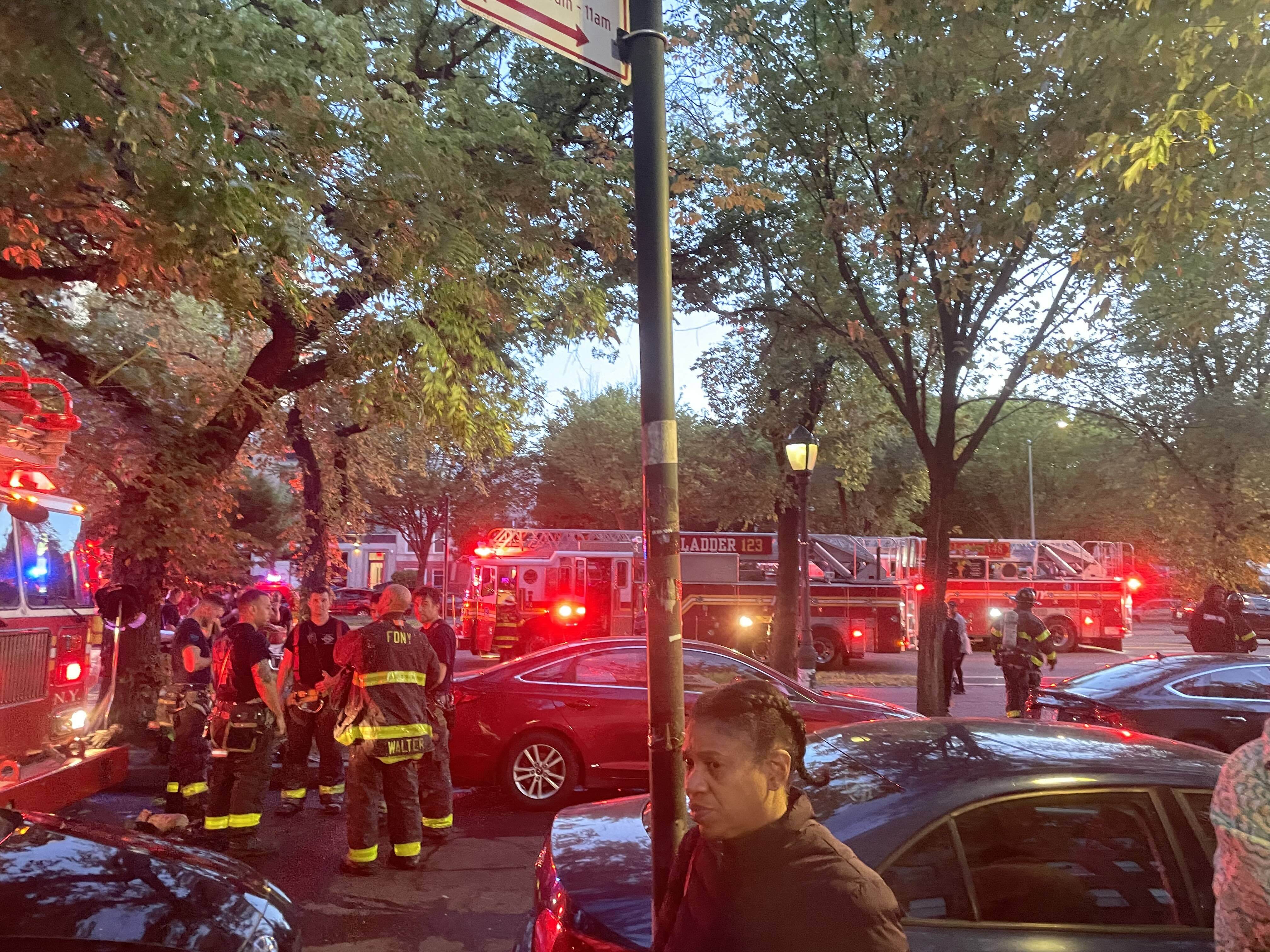 Firefighters stand outside a fire truck with emergency lights flashing