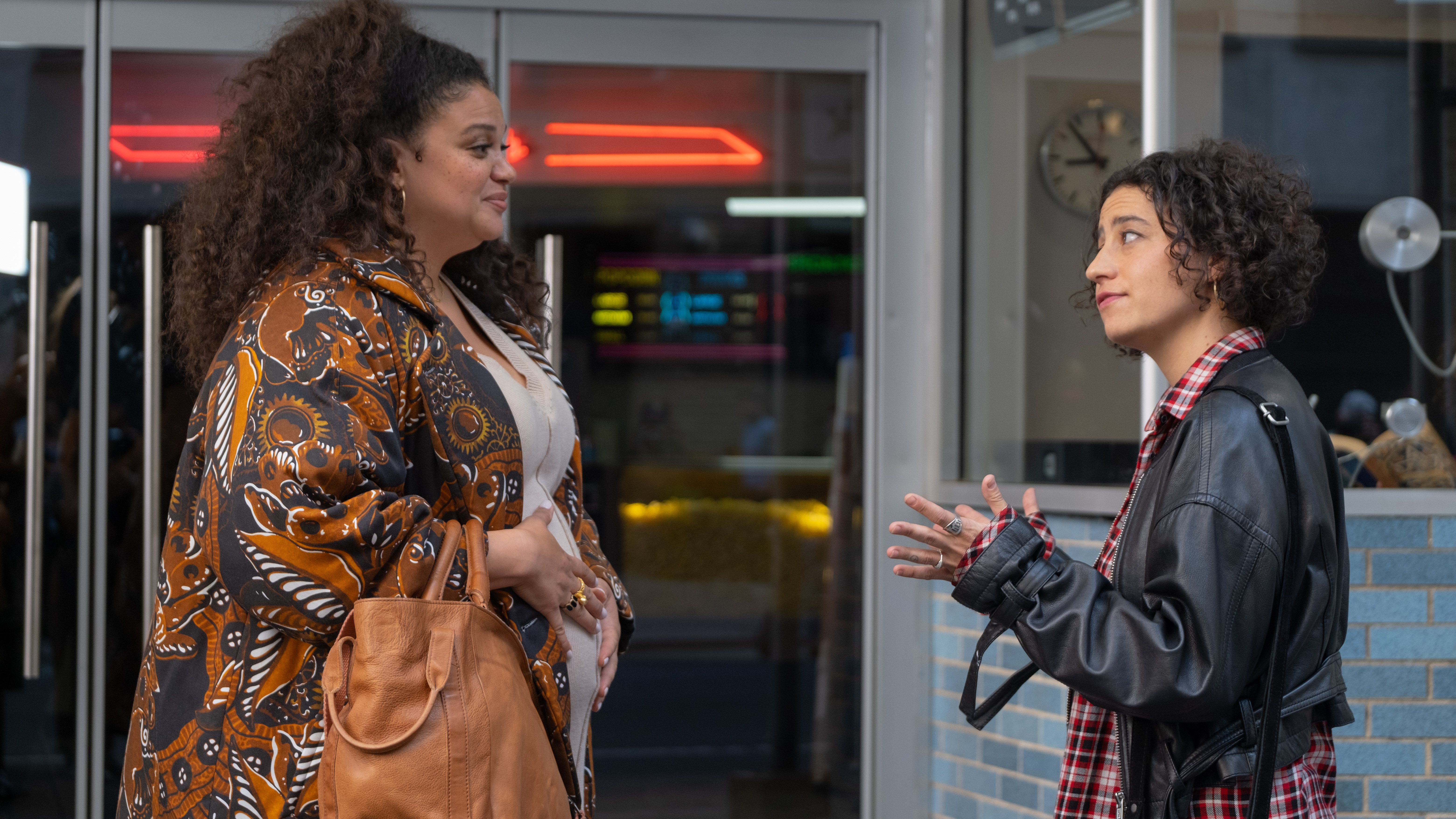 Two women stand outside and talk to each other.