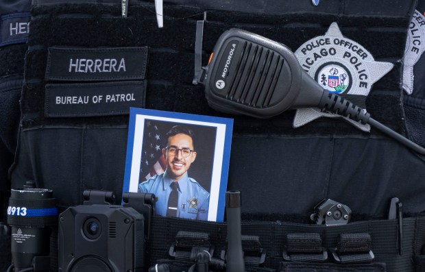 A police officer carries a picture of slain Officer Luis M. Huesca during his visitation on April 28, 2024, at Blake-Lamb Funeral Home in Oak Lawn. (Brian Cassella/Chicago Tribune)