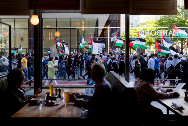 People watch from inside The Dearborn restaurant as pro Palestine activists march following the 3rd annual Palestinian flag raising ceremony on Saturday, May 11, 2024, at the Daley Plaza in Chicago. (Vincent Alban/Chicago Tribune)