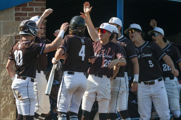Mount Carmel's Timmy Harrigan (4) is greeted by his teammates after scoring a run during the Class 4A Reavis Regional semifinal against Oak Lawn in Burbank on Thursday, May 23, 2024. (Troy Stolt/for the Daily Southtown)