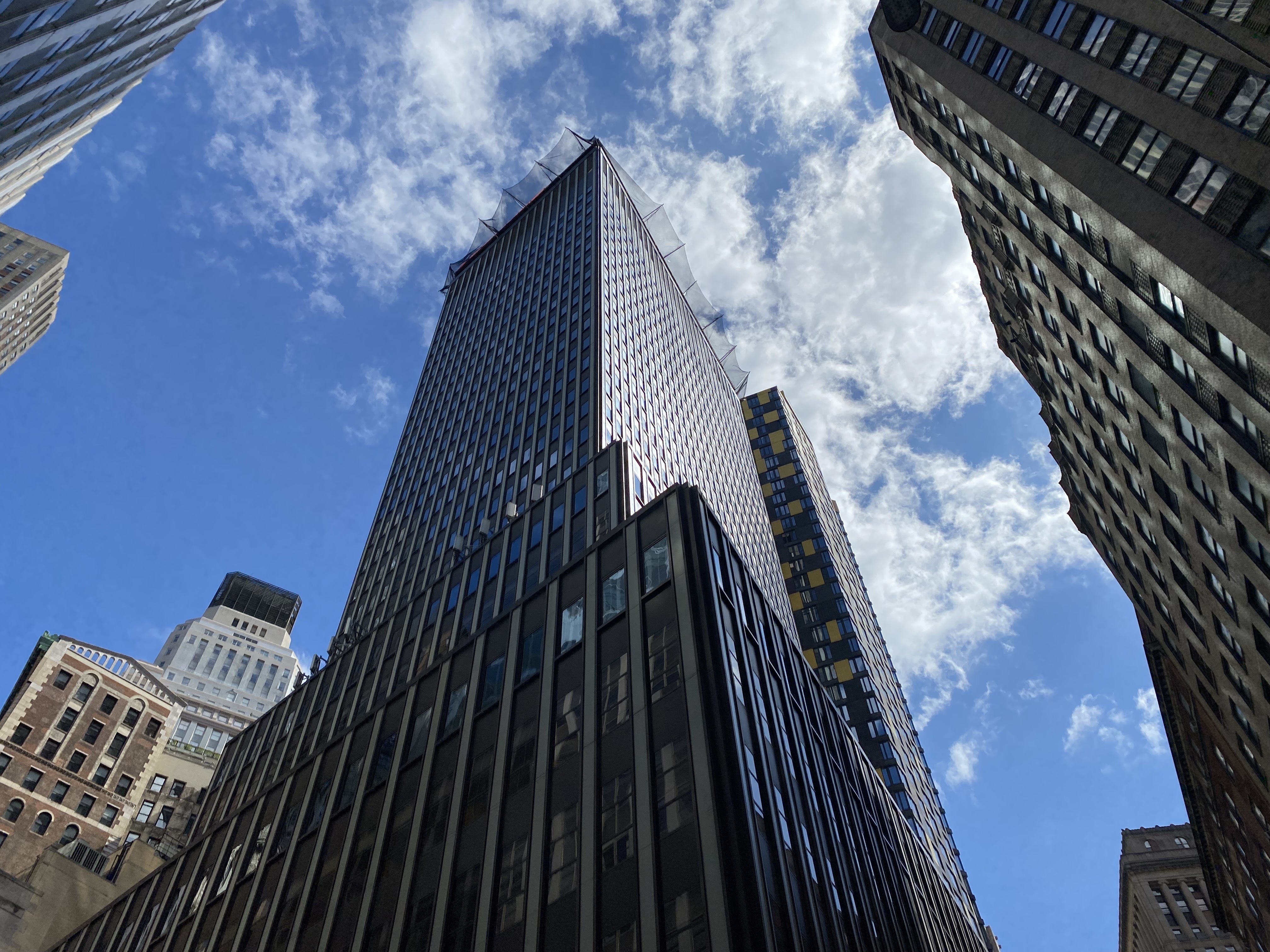 The hulking tower at 55 Broad Street reflects the sunny blue sky.