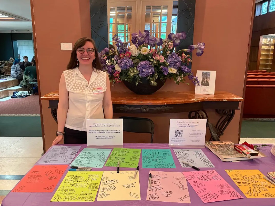 A woman stands in front of a table with colorful papers arranged.