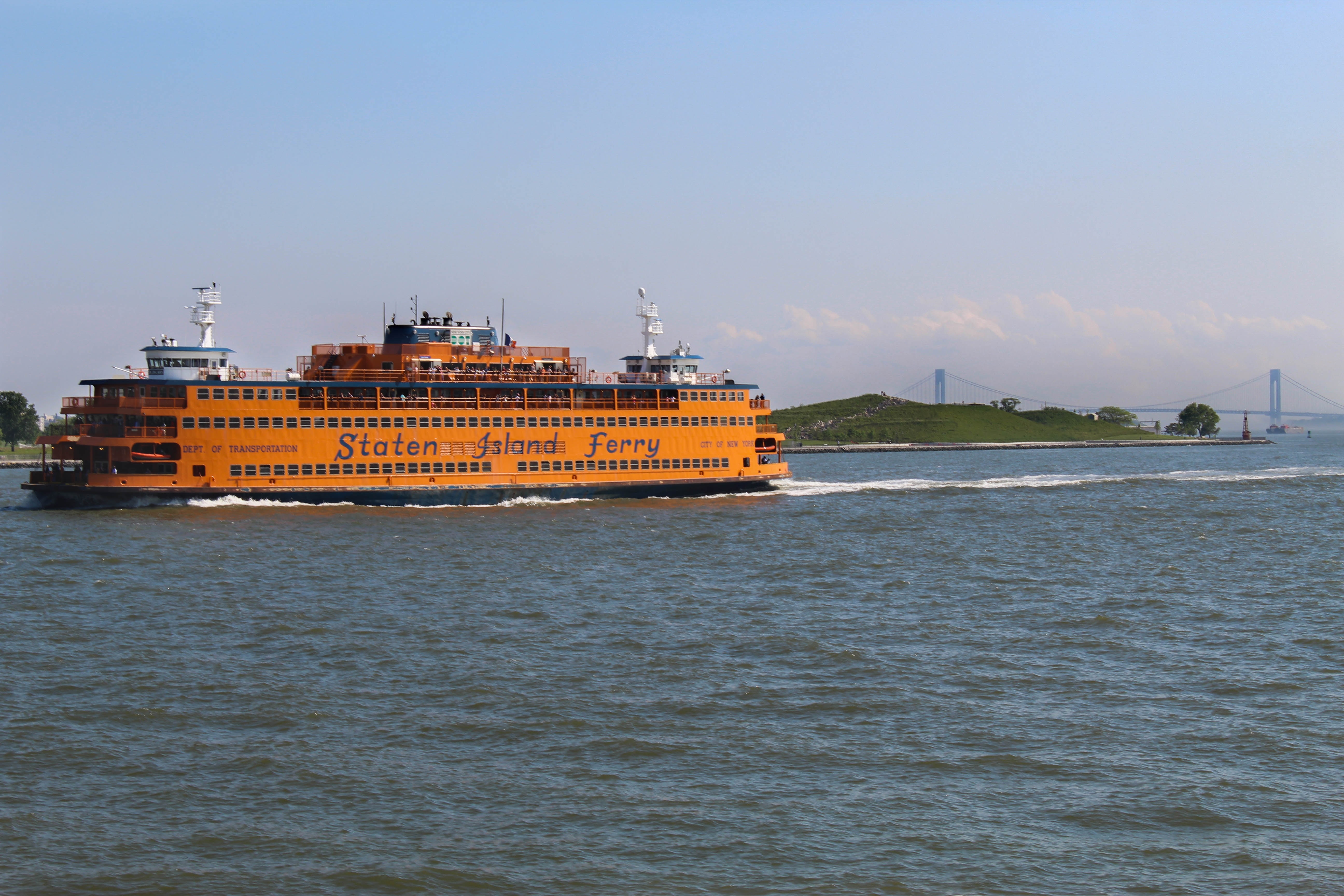 A view of an orange Staten Island Ferry boat on the water.