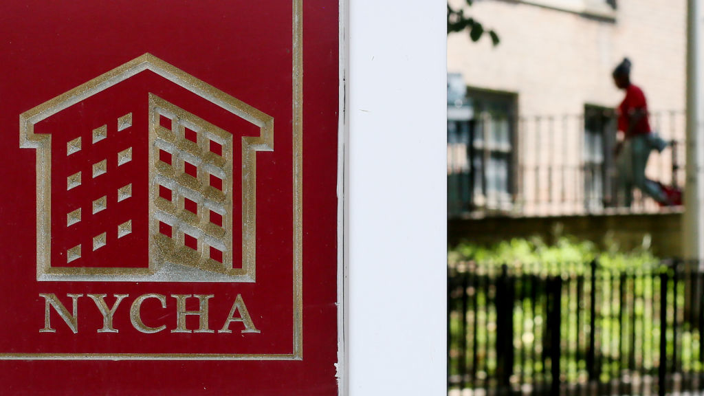 A red NYCHA sign hangs in front of a building.