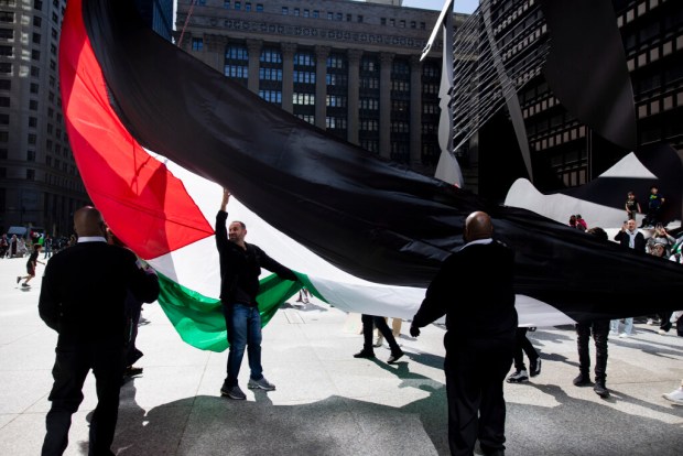 Issam Saadeh, second from left, helps to raise the flag during the 3rd annual Palestinian flag raising ceremony on Saturday, May 11, 2024, at the Daley Plaza in Chicago. (Vincent Alban/Chicago Tribune)