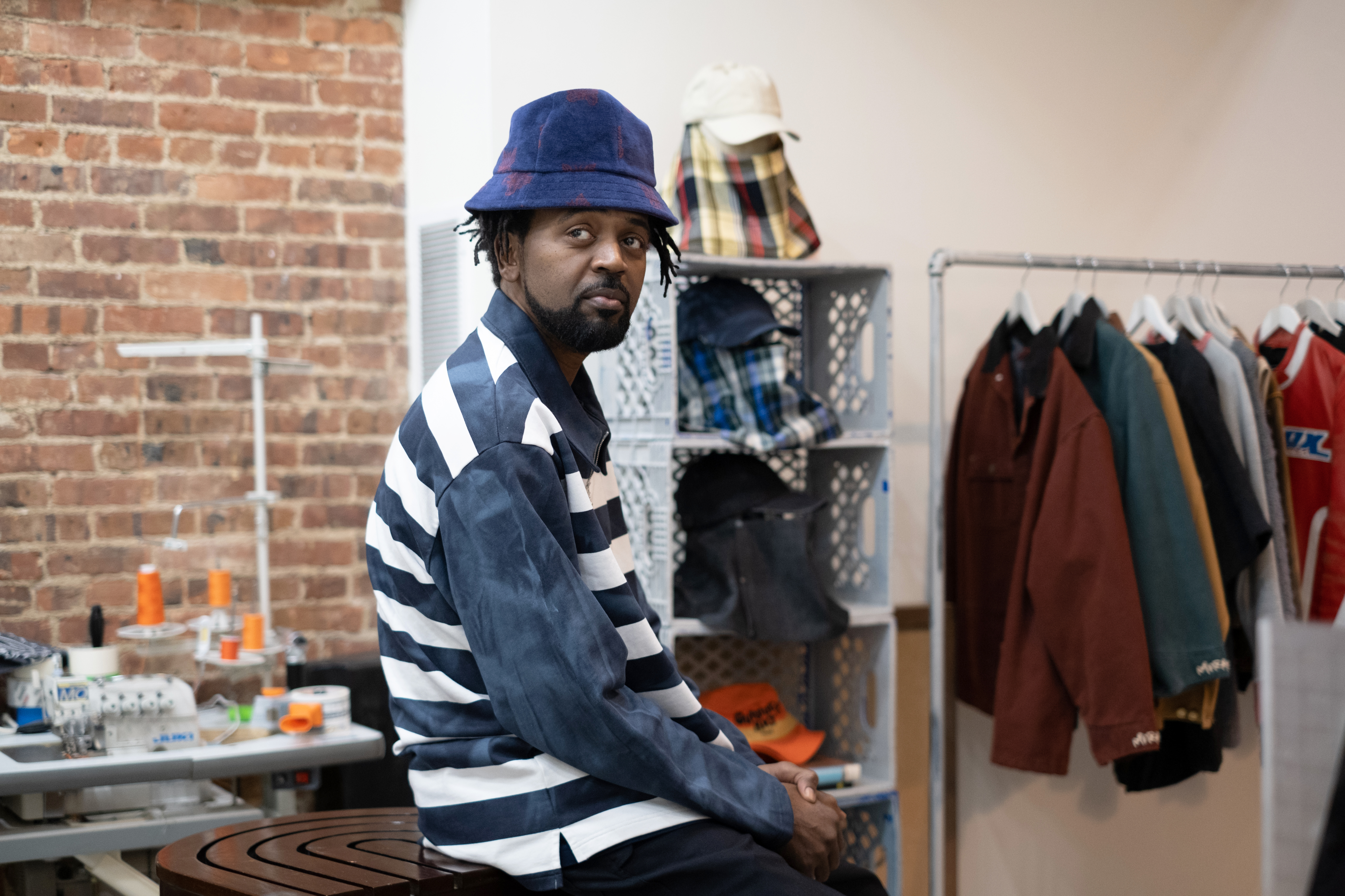 A profile of a man wearing a striped sweatshirt and bucket hat.