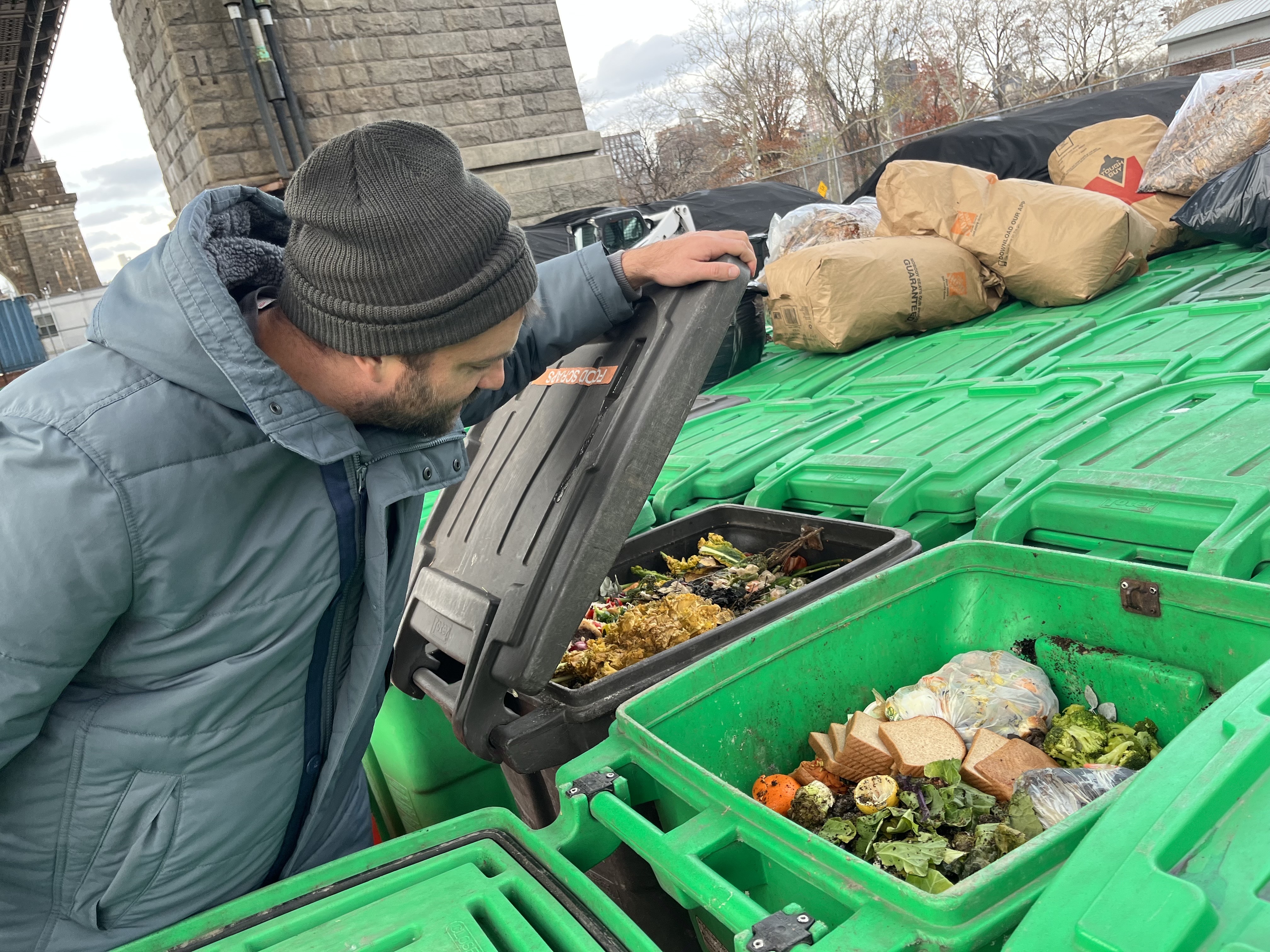 NYC Compost Project Manager Devin Reitsma examines food scraps from collection sites at greenmarkets that come to the Big Reuse composting site under the Queensborough Bridge.