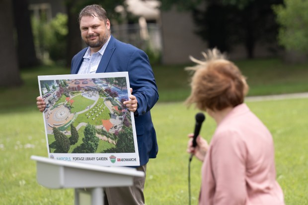 Porter County Public Library System director Jesse Butz holds up a sign featuring a rendering of the proposed Portage Library Garden as Portage Mayor Sue Lynch speaks during a groundbreaking ceremony on Thursday, July 20, 2023. (Kyle Telechan for the Post-Tribune)