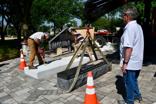 Workers from Sure-Set Monument Service recently prepare to set one of two new monuments at Montgomery Park in Montgomery. The monuments, one of which will honor veterans and the other first responders and essential workers, are part of improvements being made to the park. (Judy Pochel / For The Beacon-News)