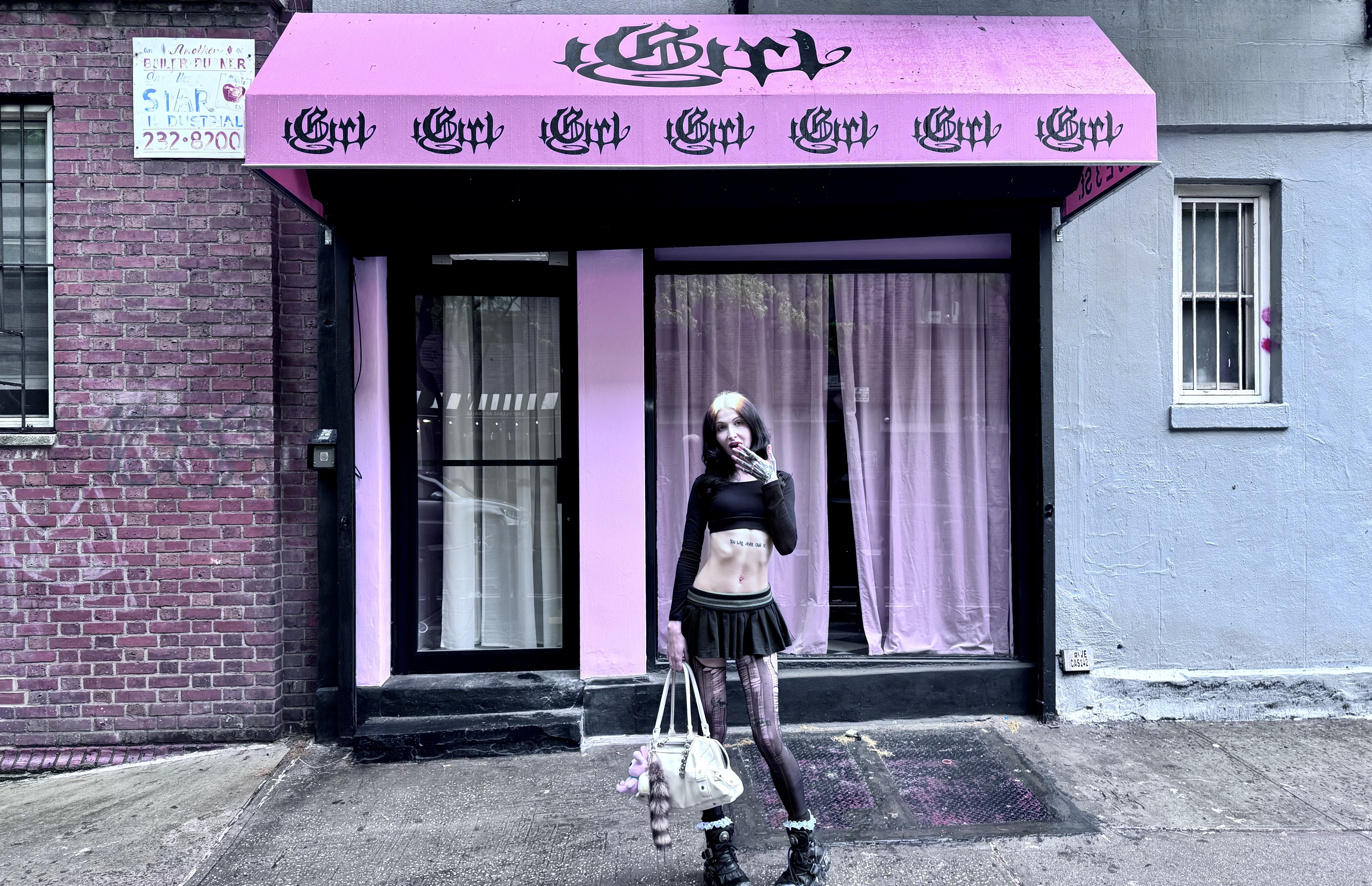 A woman stands in front of a store with a pink awning.