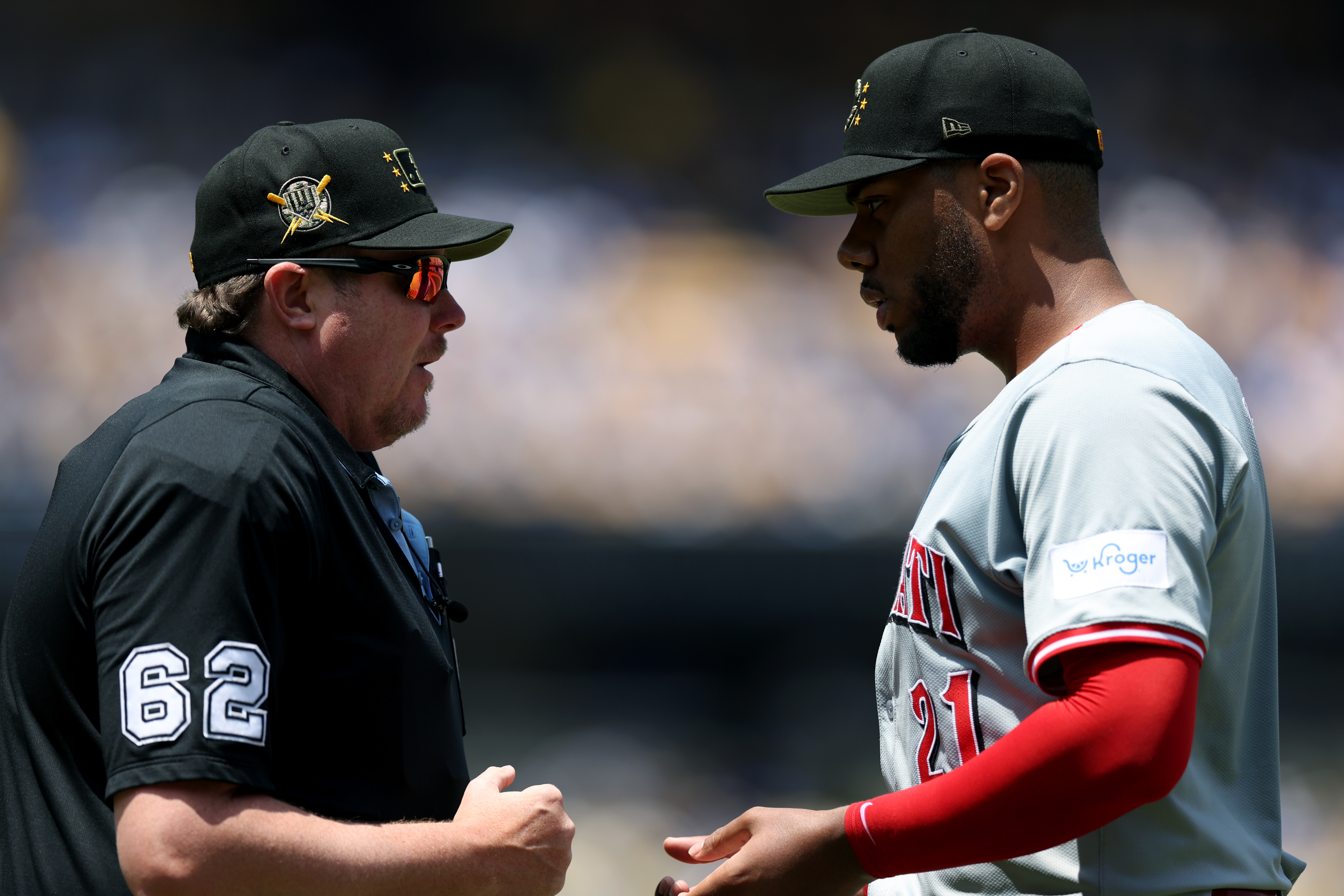 Hunter Greene #21 of the Cincinnati Reds speaks with umpire...