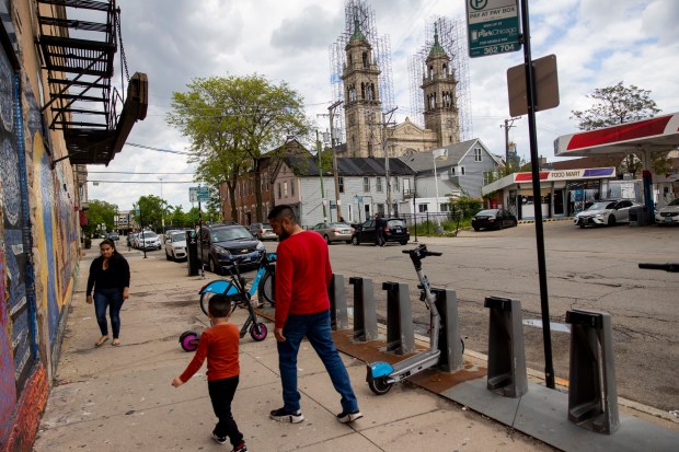People walk nearby the looming figure of St. Adalbert Church on May 10, 2024, in the Pilsen neighborhood of Chicago. (Vincent Alban/Chicago Tribune)