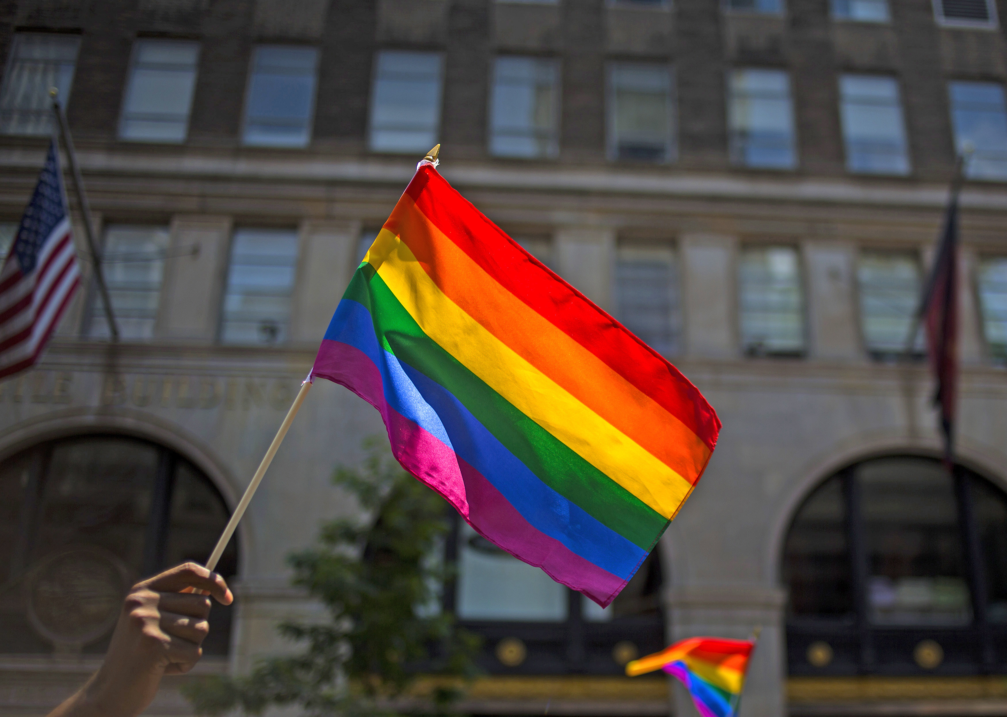 A rainbow flag is held in the air.