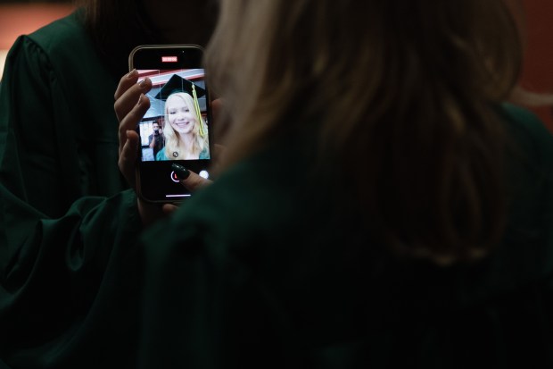 Glenbrook North graduate Mae Smolik records herself on a phone camera before graduation begins at Rosemont Theatre on Sunday, June 2, 2024. (Troy Stolt/for the Pioneer Press)