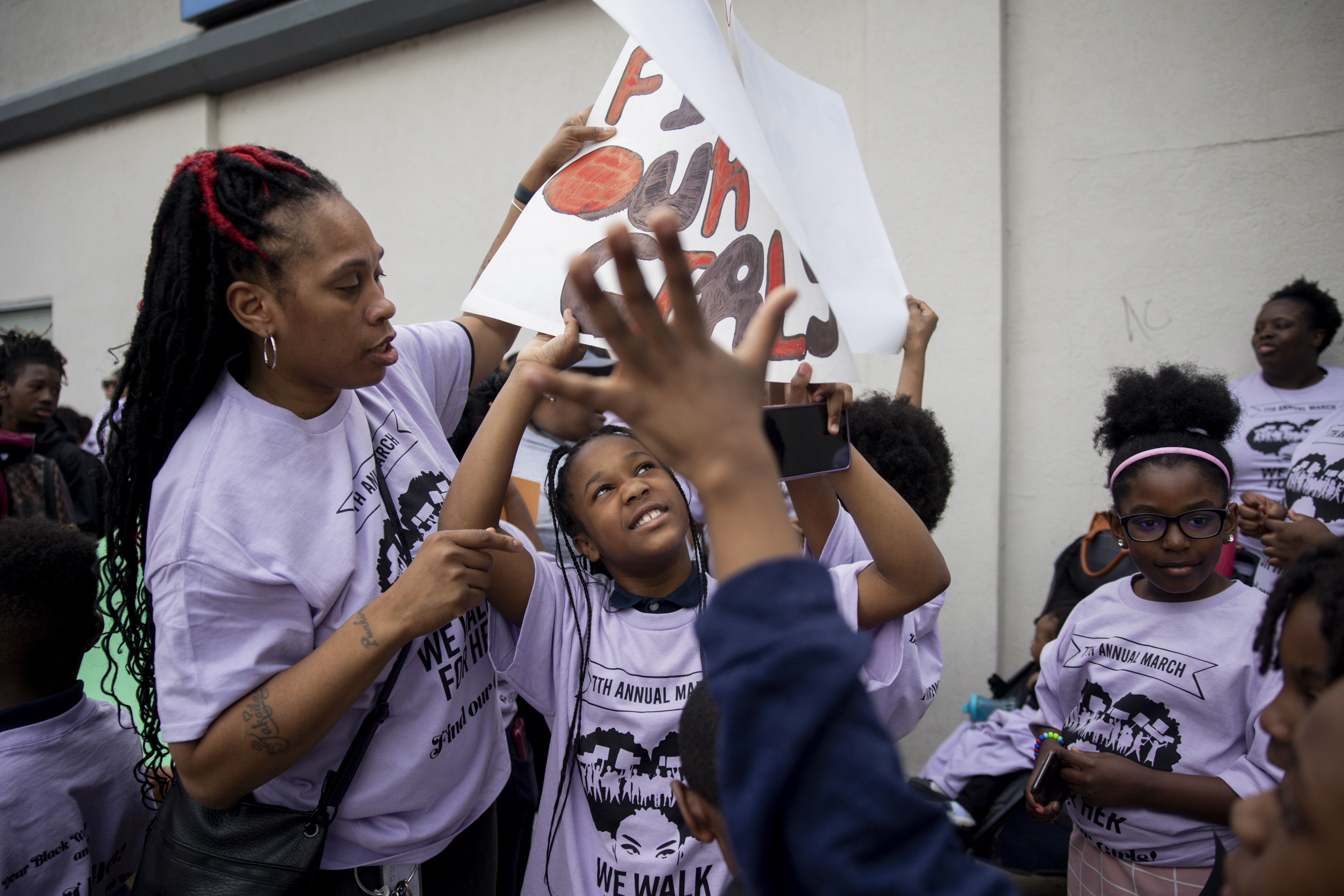 Patrice Wade, left, passes a handmade sign to Rakiyah Lashley,...