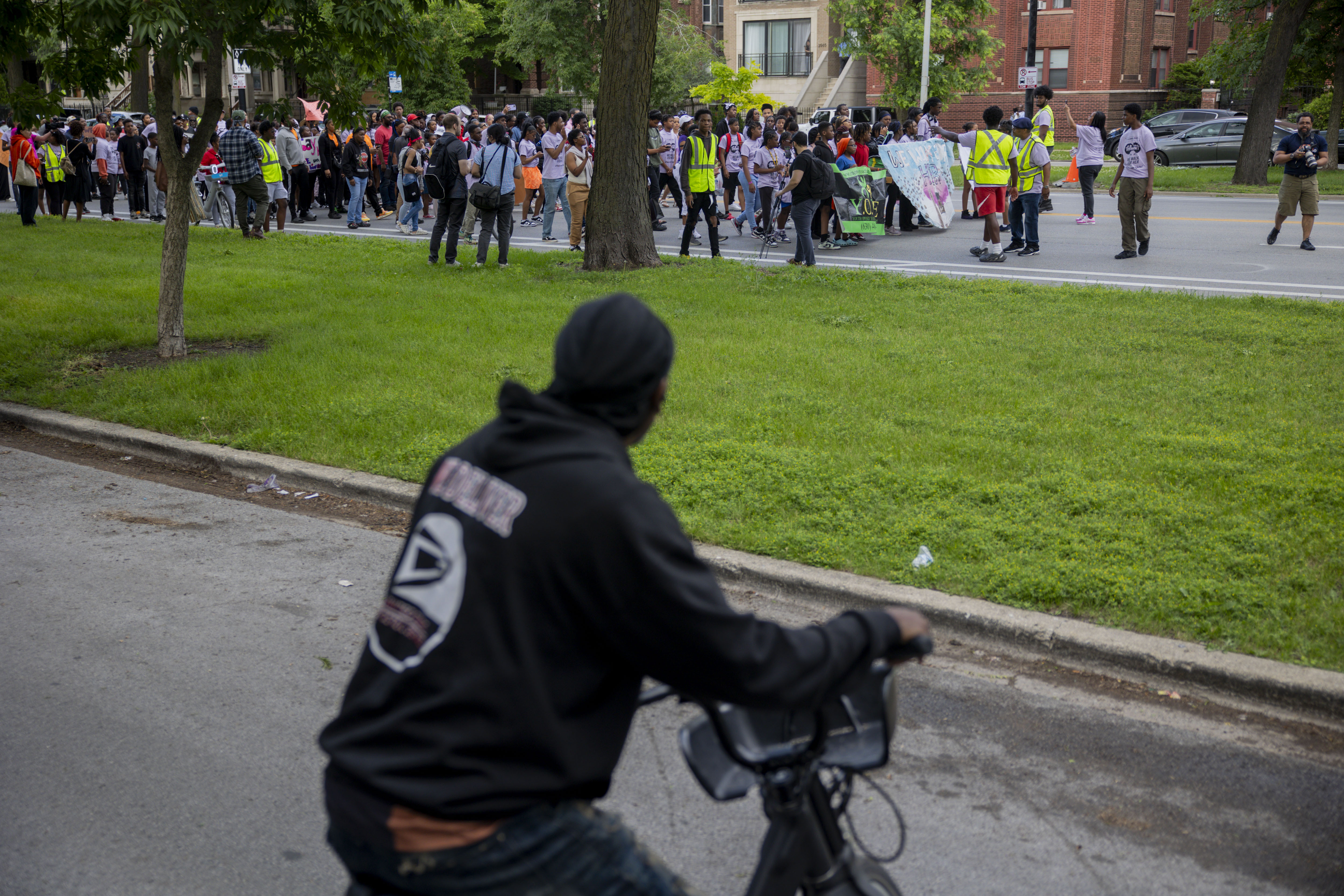 A bicyclists looks on as community members and activists march...