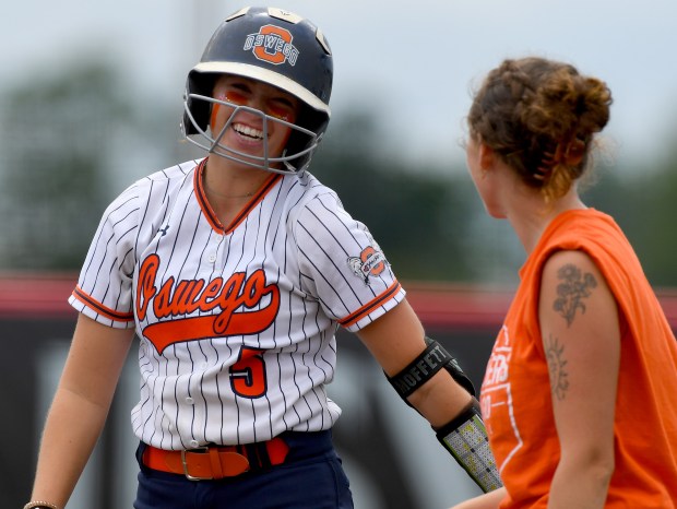 Oswego's Marissa Moffett (5) hits a RBI single and celebrates with first base coach Hailey Morland. Oswego defeated Mundelein 12-7 in the Class 4A third-place game at Louisville Slugger Sports Complex in Peoria.(Rob Dicker / Daily Southtown)