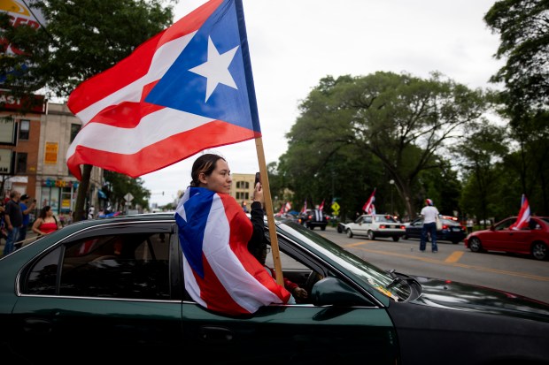 A parade attendee participates in a car caravan on W North Ave. during the 46th Puerto Rican People's Day Parade on June 8, 2024, in Humboldt Park in Chicago. (Vincent Alban/Chicago Tribune)