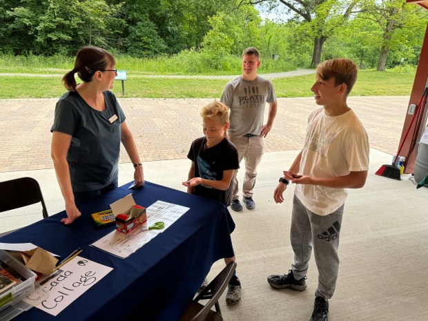 From left, Sarah Pavlovic, volunteer naturalist for Shirley Heinze Land Trust, talks with Matthew Plath, 12, Eric Plath,1 6 and their dad, Dan Plath, of Michigan City, at Cicadapalooza on Saturday, June 8, 2024, held at Meadowbrook Nature Preserve. Eric and Matthew caught some cicadas in the forest and were learning about body parts. (Deena Lawley-Dixon/for Post-Tribune)