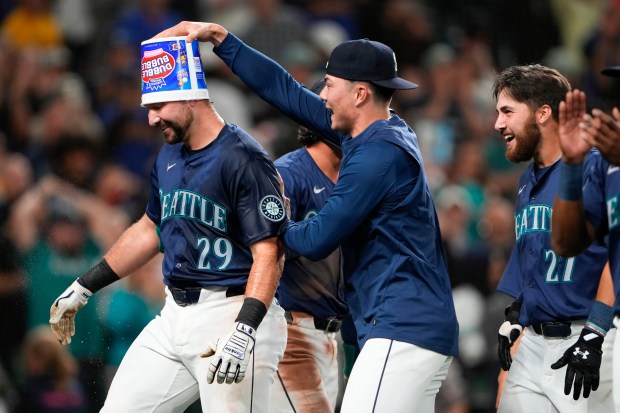 Mariners' Cal Raleigh has a bubble gum bucket put on his head by pitcher Bryan Woo as they celebrate Raleigh's game-winning grand slam for an 8-4 win against the White Sox on June 10, 2024, in Seattle. (AP Photo/Lindsey Wasson)