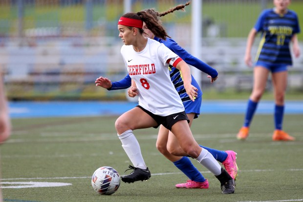 Deerfield's Emily Fox (8), dribbling away from Warren's Sofia Orgen (blue), during the soccer game on Thursday, May 9, 2024, in Gurnee. (Mark Ukena for the Lake County News-Sun)