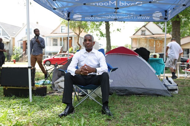 Ald. David Moore, 17th, sits next to a tent where he plans to sleep for several nights, in the 1200 block of West 73rd Place, June 15, 2024, in Chicago. Moore has set up an encampment to bring attention to violent crime and drug dealing in the neighborhood. (John J. Kim/Chicago Tribune)