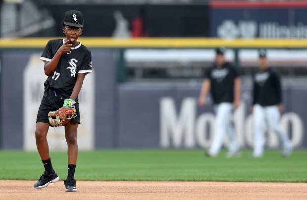 A member of the White Sox Amateur City Elite Program sticks out his tongue toward one of his teammates as the young players wait patiently for Sox players to take the field at each position to start a game against the Houston Astros at Guaranteed Rate Field in Chicago on June 19, 2024. (Chris Sweda/Chicago Tribune)