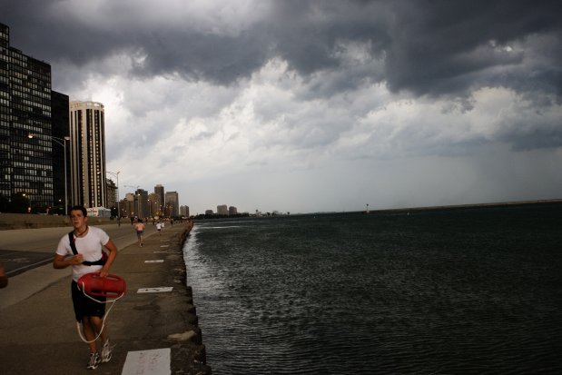 A lifeguard runs south down the lakefront bike path ready for a possible seiche as dark clouds move out over the lakefront at Chicago Avenue on July 2, 2008. A seiche alert closed the beaches. (Alex Garcia/Chicago Tribune)