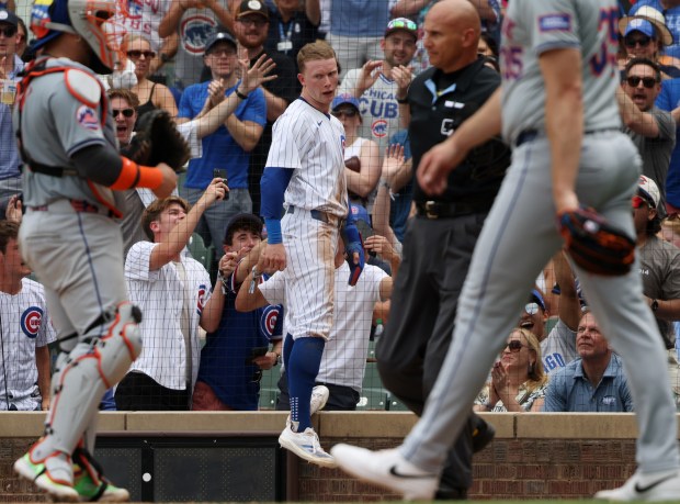 Cubs centerfielder Pete Crow-Armstrong, center, jumps off the brick guardrail after scoring on an RBI double by catcher Tomás Nido in the sixth inning against the Mets at Wrigley Field on June 22, 2024, in Chicago. (John J. Kim/Chicago Tribune)