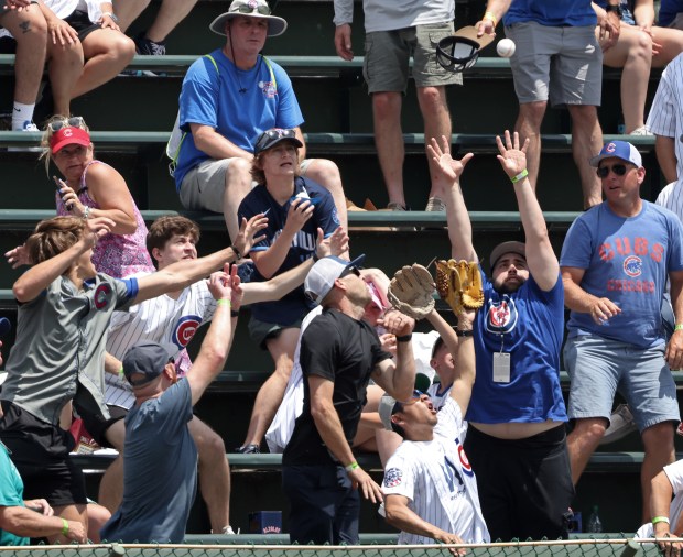 Fans reach for a batting practice home run ball before a game between the Cubs and Mets at Wrigley Field on June 22, 2024, in Chicago. (John J. Kim/Chicago Tribune)