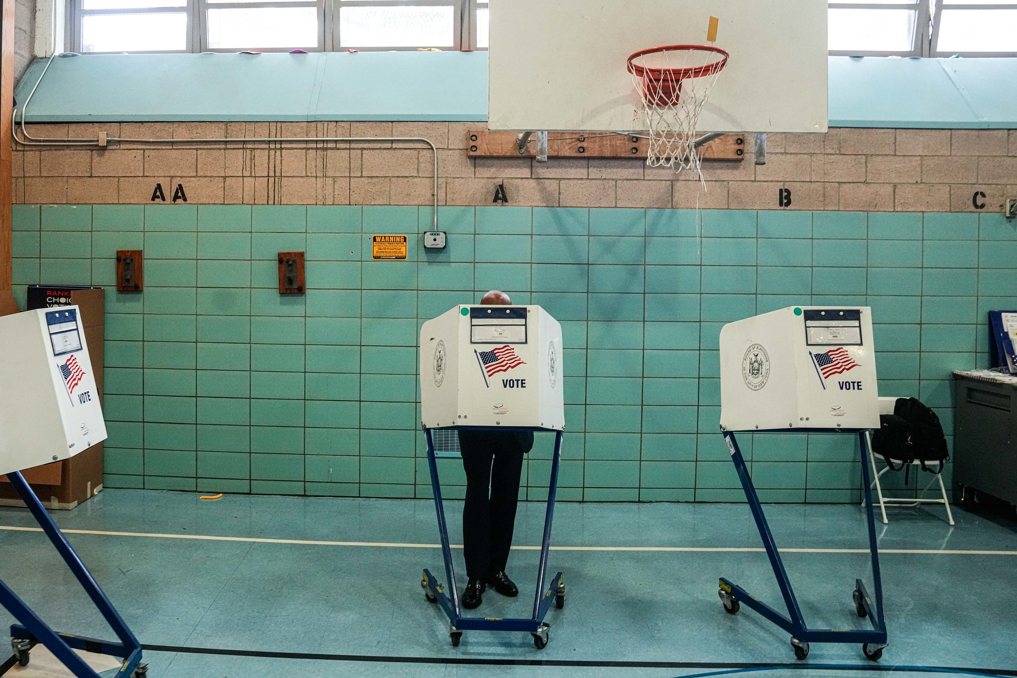 Voting machines in a gymnasium with a teal background and floor