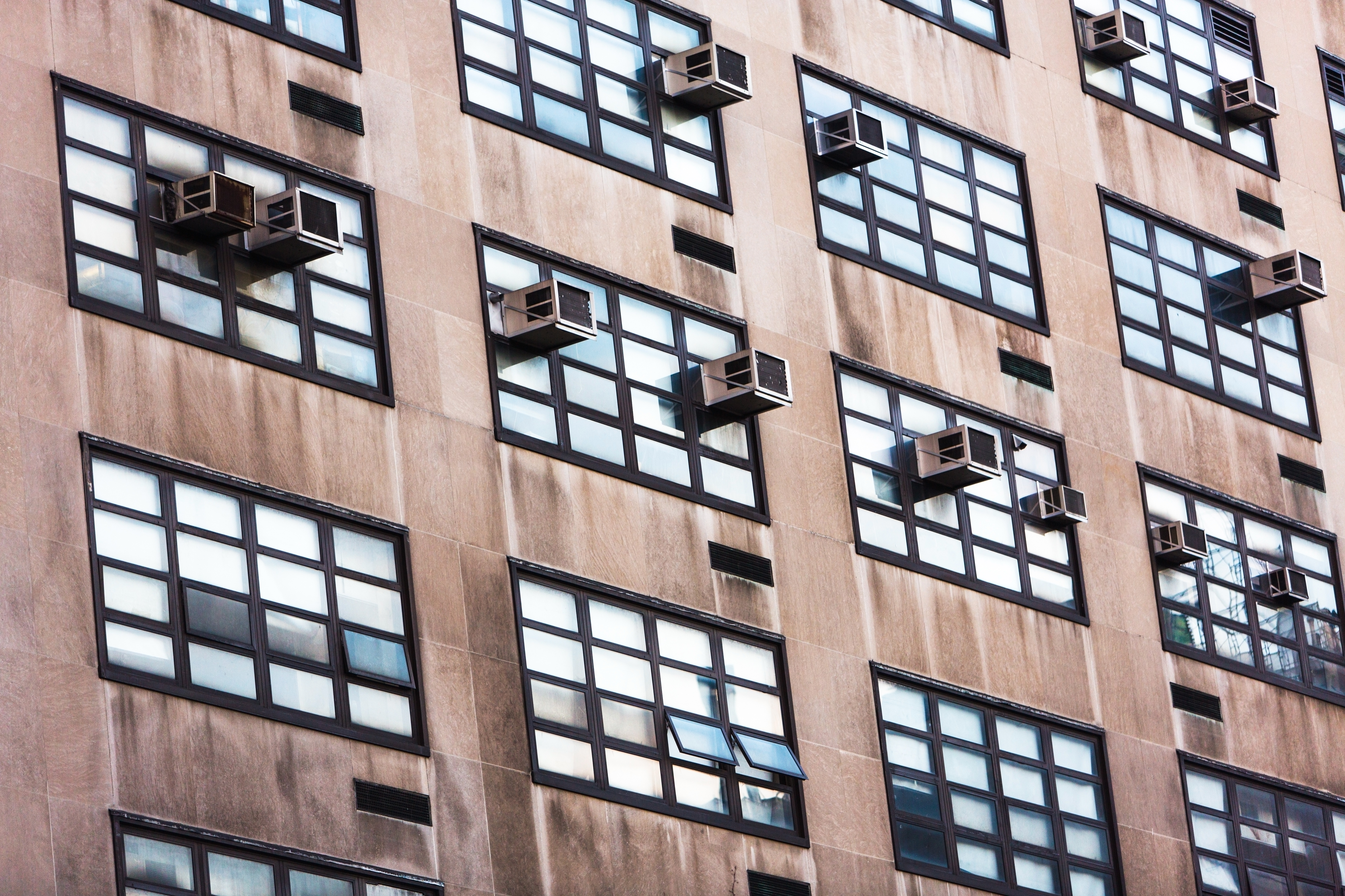 Air conditioners in the windows of a large building.