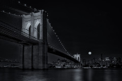 Full moon rises over the Brooklyn Bridge.